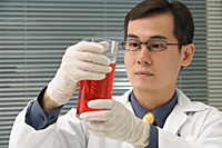 Scientist examining container of fluid - Asia Images Group