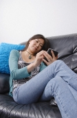 Young woman sitting on couch using organizer - Asia Images Group