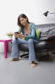 Young woman sitting on couch using organizer - Asia Images Group