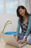 Young woman sitting on floor using laptop - Asia Images Group