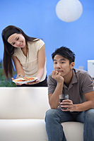 Young woman offering man a plate of food - Asia Images Group
