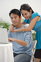 Young woman leaning on shoulder of man at the computer - Asia Images Group