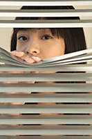 Young woman behind Venetian blinds - Asia Images Group