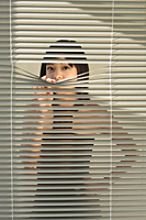 Young woman behind Venetian blinds - Asia Images Group