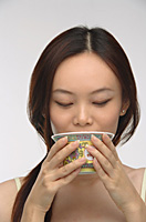 Young woman drinking tea from traditional tea cup - Asia Images Group