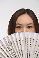Young woman with fan looking at camera - Asia Images Group