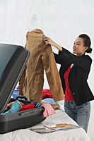 Young woman packing suitcase - Asia Images Group