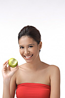 Young woman smiling at camera holding apple - Asia Images Group