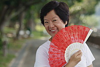 Woman with fan smiling at camera - Asia Images Group