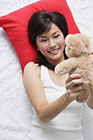 Young woman playing with teddy - Asia Images Group