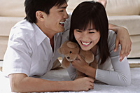 Young couple laughing while hugging and lying on the floor - Asia Images Group