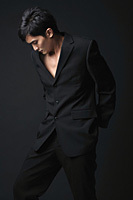 Young man in black suit looking down - Asia Images Group