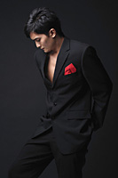 Young man in black suit looking down - Asia Images Group