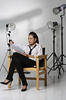Young woman sitting in chair and studying paper - Asia Images Group