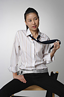 Young woman sitting and playing with tie - Asia Images Group