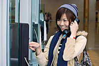 Young woman on public phone at the airport - Asia Images Group