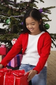 Girl looking at Christmas presents with smile - Asia Images Group