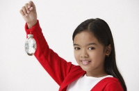 Girl holding up Christmas ornament looking at camera - Asia Images Group