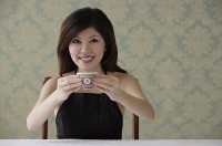 Young woman holding teacup with both hands - Asia Images Group