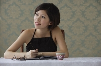 Young woman looking sideways while writing - Asia Images Group