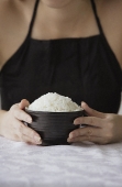Young woman holding bowl of rice with both hands - Asia Images Group