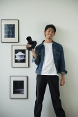 Young man with camera, smiling at camera - Asia Images Group