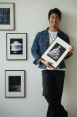 Young man holding framed photographs - Asia Images Group