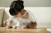 Girl in white dress playing with tea cups - Asia Images Group