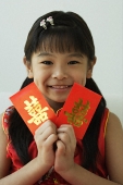Girl with double happiness red packet, smiling at camera - Asia Images Group