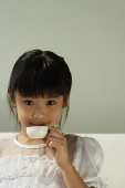 Girl drinking from tiny cup - Asia Images Group