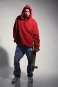 young man wearing red hooded sweatshirt holding skateboard - Asia Images Group