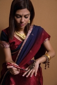 Indian woman painting hand with henna - Asia Images Group