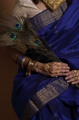 Torso of Indian woman holding peacock feathers - Asia Images Group