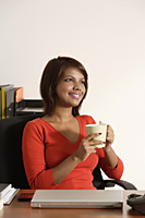 Business woman holding coffee mug, smiling - Asia Images Group