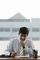 business man writing at his desk - Asia Images Group
