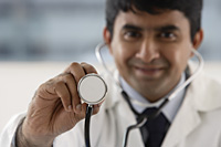 doctor holding up stethoscope - Asia Images Group
