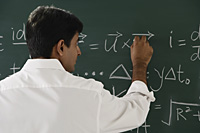 teacher writing formulas on chalkboard - Asia Images Group