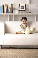 young toddler playing with soft toy on the couch - Asia Images Group