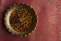 Indian digestive mukhwa seeds on brass dish on pink sari cloth - Asia Images Group