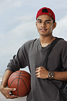 young man with red cap holding basket ball and carrying backpack - Asia Images Group