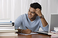 young man sitting at his desk, writing - Asia Images Group
