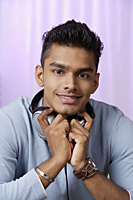 young man with headphones around his neck, smiling at camera - Asia Images Group
