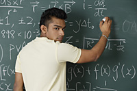 young man writing formulas on chalk board - Asia Images Group