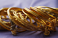 gold Indian bangles on purple sari cloth - Asia Images Group