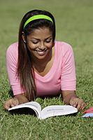 Young woman laying on grass reading a book - Asia Images Group