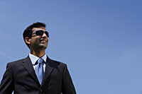Indian businessman wearing sunglasses and smiling outside. - Asia Images Group
