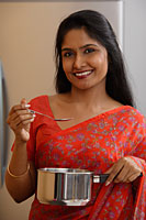 Indian woman wearing sari while preparing food. - Asia Images Group