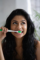 Head shot of Indian woman brushing her teeth and looking up - Asia Images Group