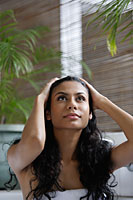Indian woman looking up and holding her head - Asia Images Group