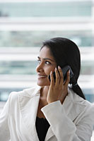 profile of an Indian woman talking on phone and smiling. - Asia Images Group